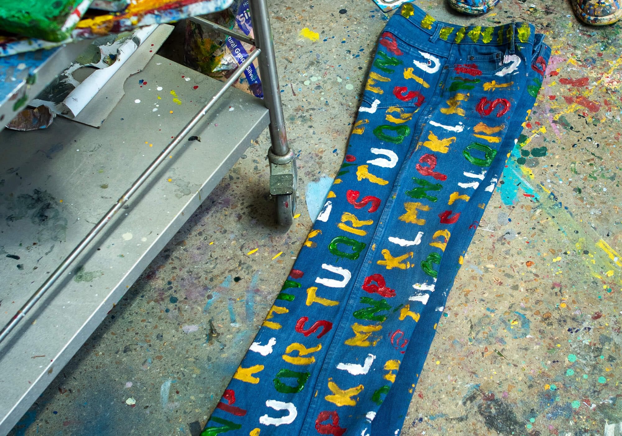 Hand-painted lettering across a pair of vintage trousers on the studio floor